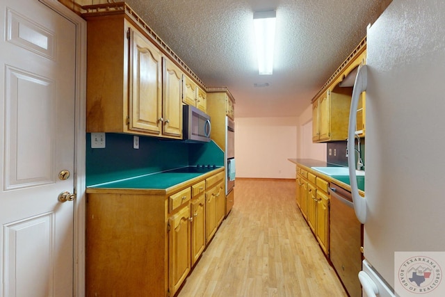 kitchen featuring light hardwood / wood-style floors, sink, a textured ceiling, and stainless steel appliances