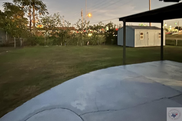 yard at dusk featuring a storage unit