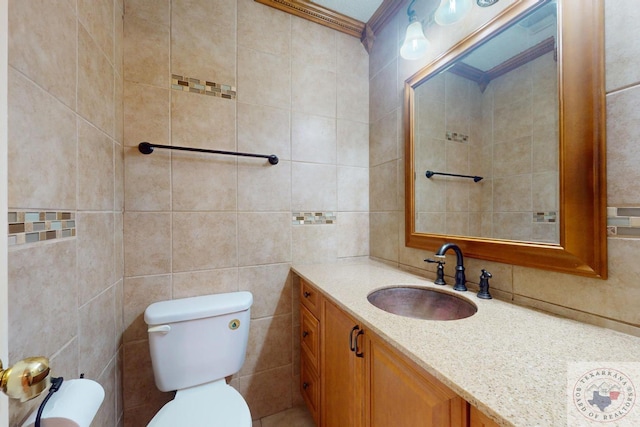 bathroom with vanity, toilet, ornamental molding, and tile walls