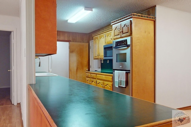 kitchen with sink, stainless steel appliances, light hardwood / wood-style floors, and a textured ceiling