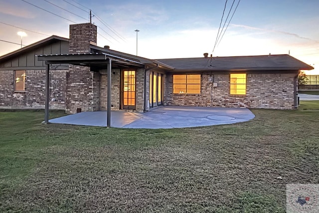 back house at dusk with a patio area and a yard