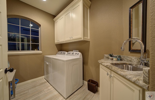 laundry area with cabinet space, a textured wall, a sink, separate washer and dryer, and baseboards