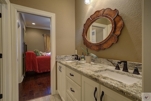 ensuite bathroom with double vanity, a textured wall, ensuite bath, wood finished floors, and a sink