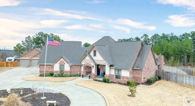 view of front facade featuring brick siding, roof with shingles, and fence