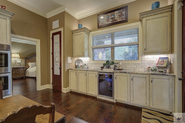 kitchen with wine cooler, cream cabinetry, ornamental molding, dark wood-type flooring, and stainless steel double oven