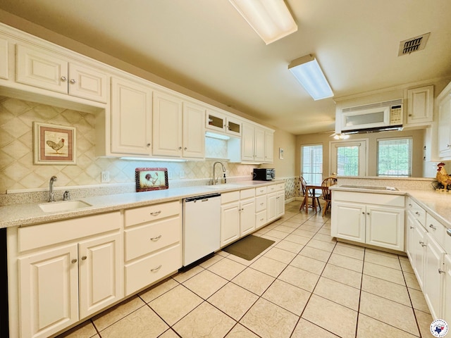 kitchen featuring tasteful backsplash, white appliances, light countertops, and a sink