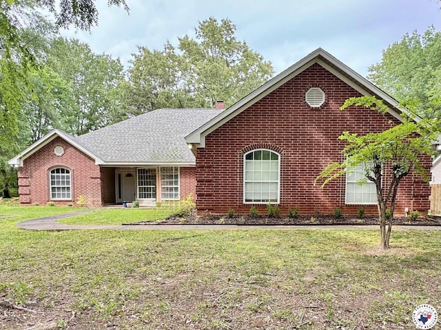 view of front of property featuring a front yard, roof with shingles, and brick siding