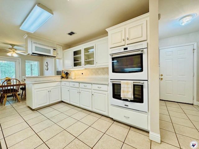 kitchen featuring visible vents, light countertops, light tile patterned flooring, white appliances, and a peninsula