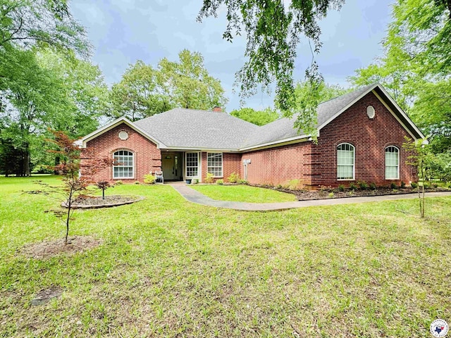 ranch-style house featuring a chimney, brick siding, a shingled roof, and a front lawn