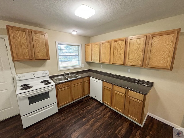 kitchen with dark wood finished floors, dark countertops, a sink, a textured ceiling, and white appliances