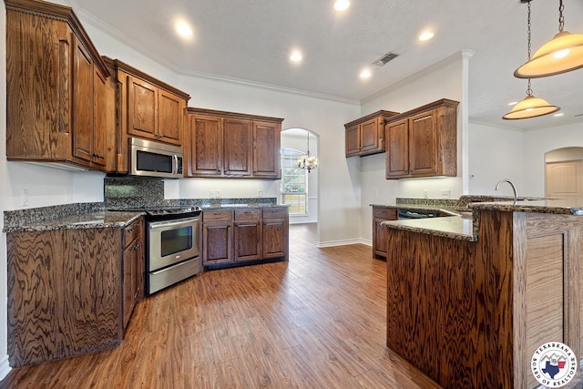 3604 Melody Ln, Texarkana, TX 75503 - kitchen featuring appliances with stainless steel finishes, arched walkways, wood finished floors, dark stone countertops, and a peninsula