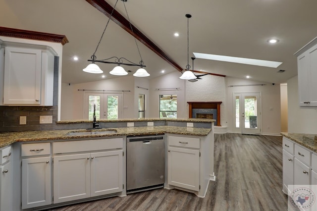 kitchen with hanging light fixtures, stainless steel dishwasher, white cabinets, sink, and lofted ceiling with beams