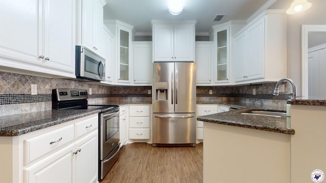 6908 Woodmere Ct, Texarkana, TX 75503 - kitchen featuring stainless steel appliances, white cabinets, light wood-type flooring, and dark stone counters