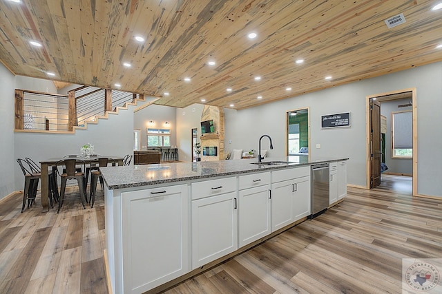 kitchen featuring white cabinets, wood ceiling, dark stone counters, an island with sink, and sink