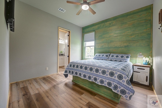 bedroom with light hardwood / wood-style floors, ensuite bathroom, and ceiling fan