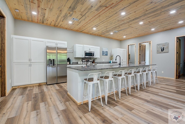 kitchen with white cabinets, appliances with stainless steel finishes, a breakfast bar, and a spacious island