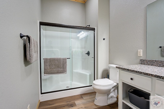 bathroom featuring vanity, toilet, a shower with shower door, and hardwood / wood-style flooring