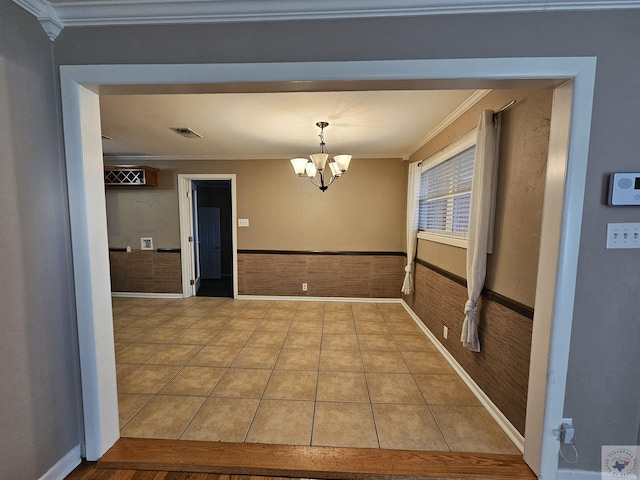 unfurnished dining area featuring crown molding, a chandelier, and light tile patterned floors