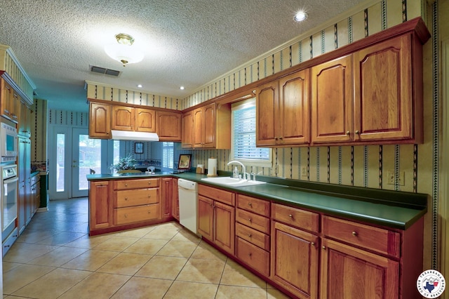 21 Holly Ridge Dr, Texarkana, TX 75503 - kitchen featuring a textured ceiling, a peninsula, dishwasher, brown cabinetry, and wallpapered walls