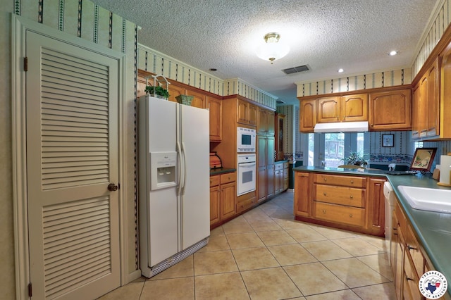 21 Holly Ridge Dr, Texarkana, TX 75503 - kitchen with white appliances, a textured ceiling, brown cabinetry, a peninsula, and dark countertops