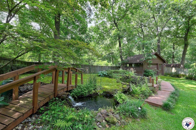 21 Holly Ridge Dr, Texarkana, TX 75503 - fenced backyard featuring a deck, an outbuilding, and a garden pond
