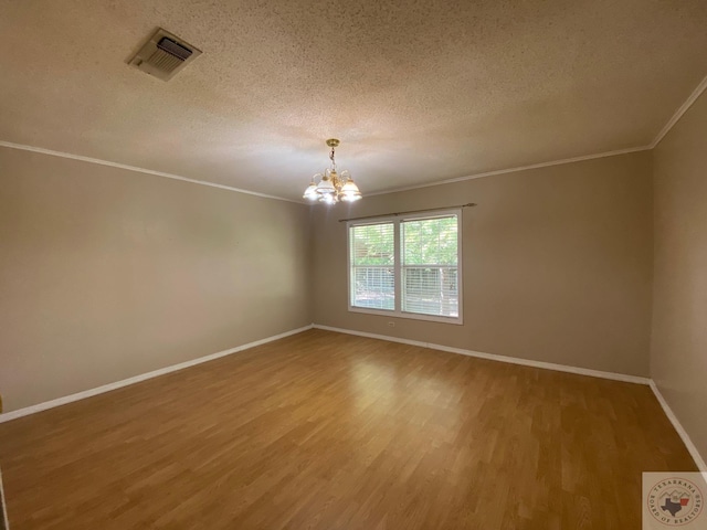 unfurnished room with a textured ceiling, hardwood / wood-style floors, a chandelier, and ornamental molding