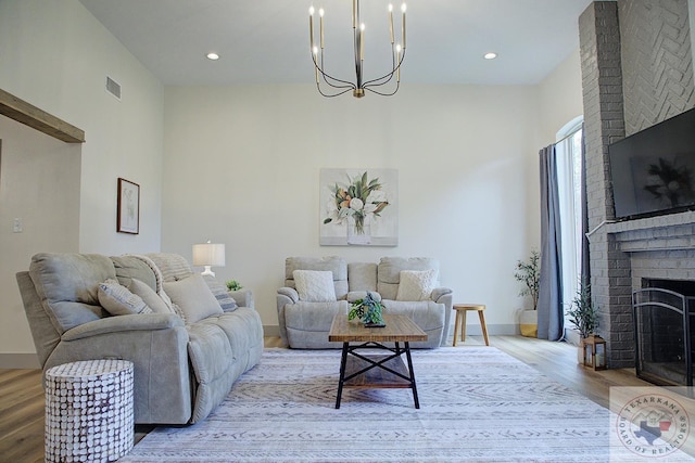 living area featuring baseboards, a brick fireplace, visible vents, and light wood-style floors