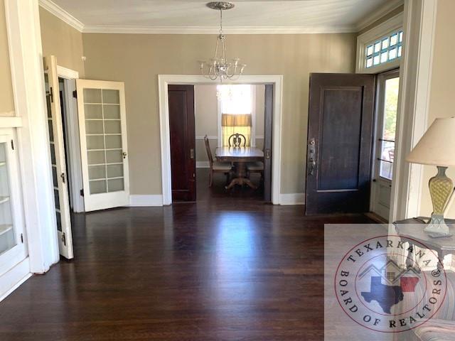 foyer featuring ornamental molding, an inviting chandelier, and dark wood-type flooring