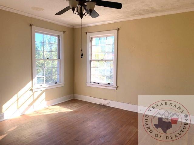 empty room with dark wood-type flooring, ceiling fan, and ornamental molding