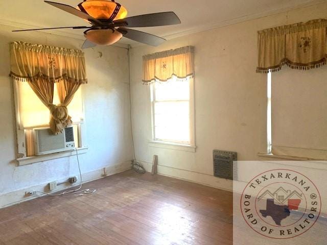 spare room featuring wood-type flooring, cooling unit, ceiling fan, and crown molding