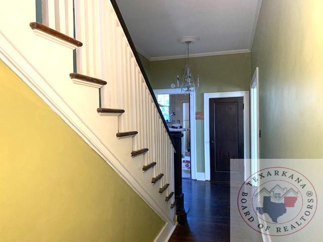 stairs featuring a chandelier, crown molding, and wood-type flooring