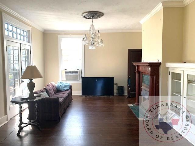 living room with crown molding, a notable chandelier, and dark hardwood / wood-style flooring