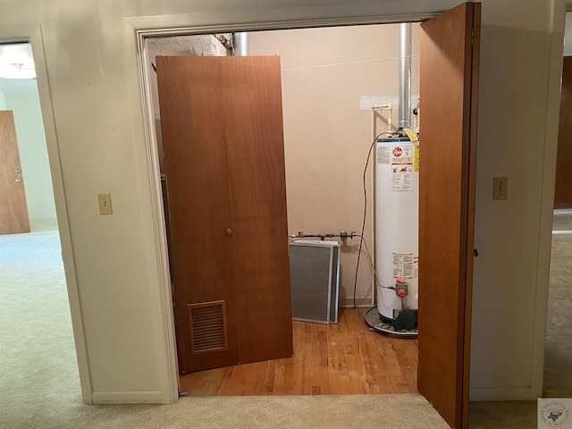 corridor featuring light colored carpet and gas water heater