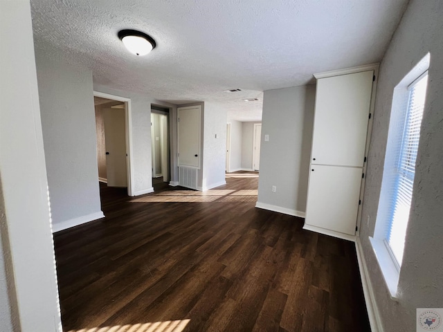 spare room featuring a textured ceiling, dark hardwood / wood-style flooring, and a wealth of natural light