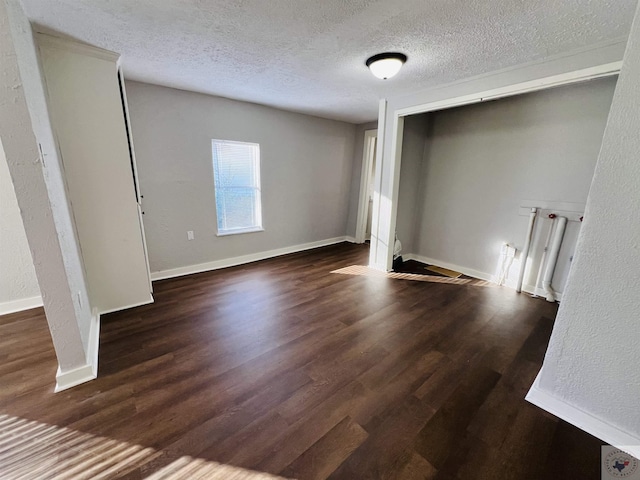 unfurnished bedroom featuring a textured ceiling and dark hardwood / wood-style floors