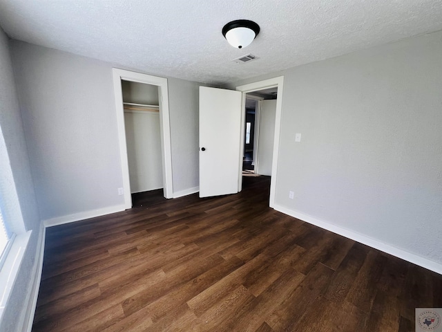 unfurnished bedroom with a closet, a textured ceiling, and dark hardwood / wood-style floors