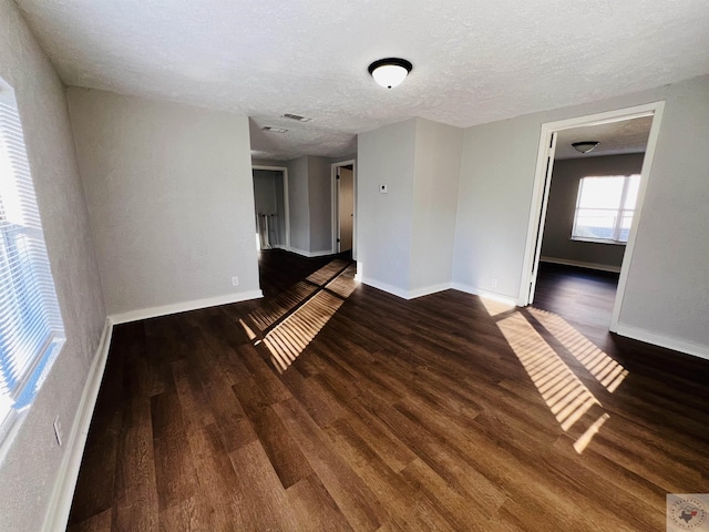 spare room featuring dark wood-type flooring and a textured ceiling