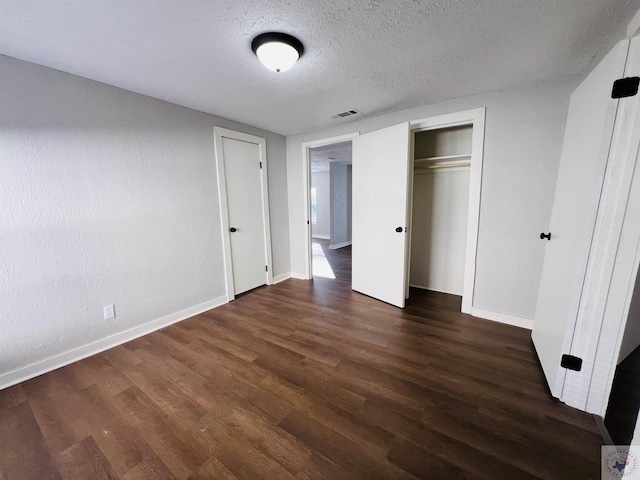 unfurnished bedroom featuring a closet, dark wood-type flooring, and a textured ceiling