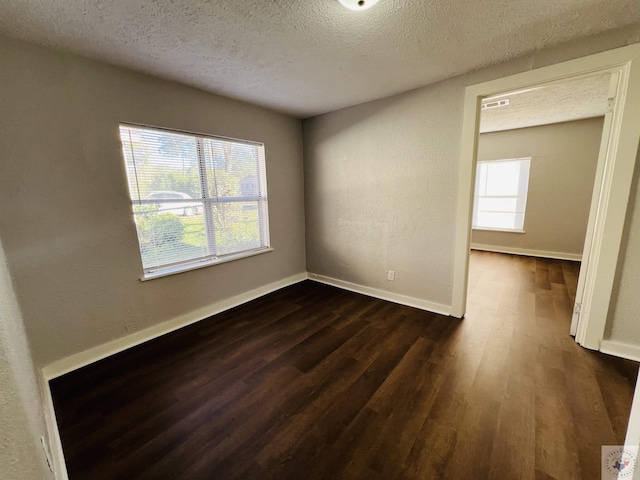 unfurnished room featuring a textured ceiling and dark hardwood / wood-style flooring