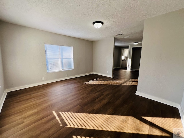 spare room featuring dark wood-type flooring and a textured ceiling