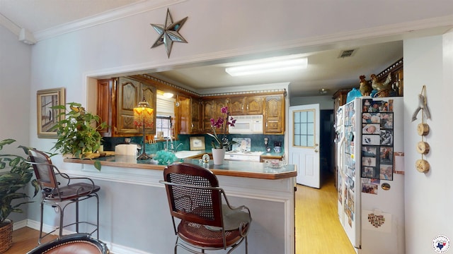 122 David Dr, New Boston, TX 75570 - kitchen with white appliances, a peninsula, light wood finished floors, ornamental molding, and a kitchen breakfast bar