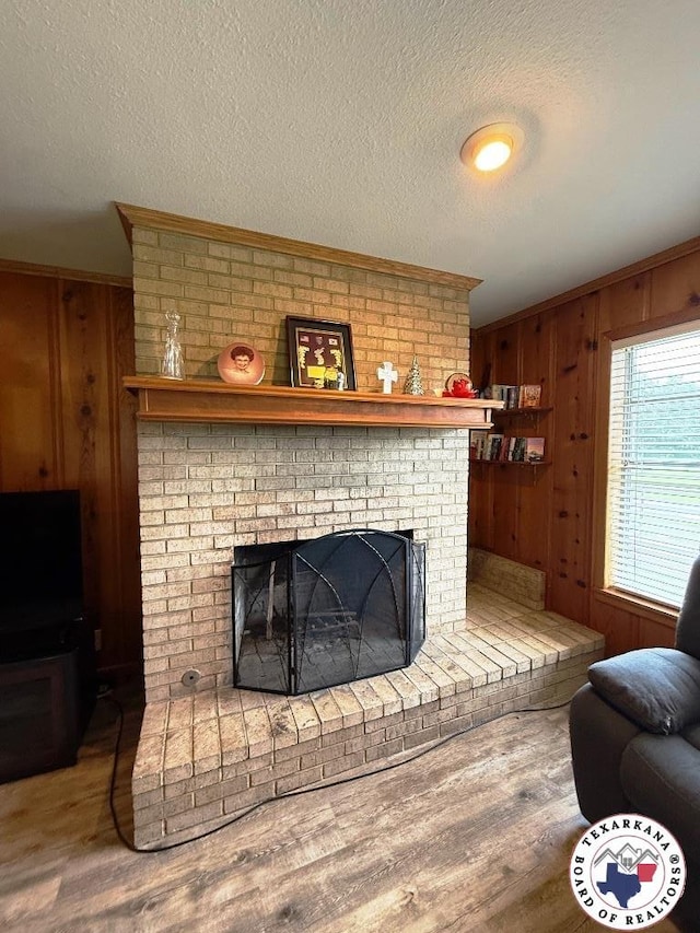 184 E Elliott Ln, Dekalb, TX 75559 - living area featuring a fireplace, wood finished floors, wood walls, a textured ceiling, and crown molding