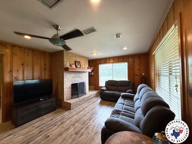 184 E Elliott Ln, Dekalb, TX 75559 - living area featuring wood walls, ceiling fan, wood finished floors, a brick fireplace, and a textured ceiling