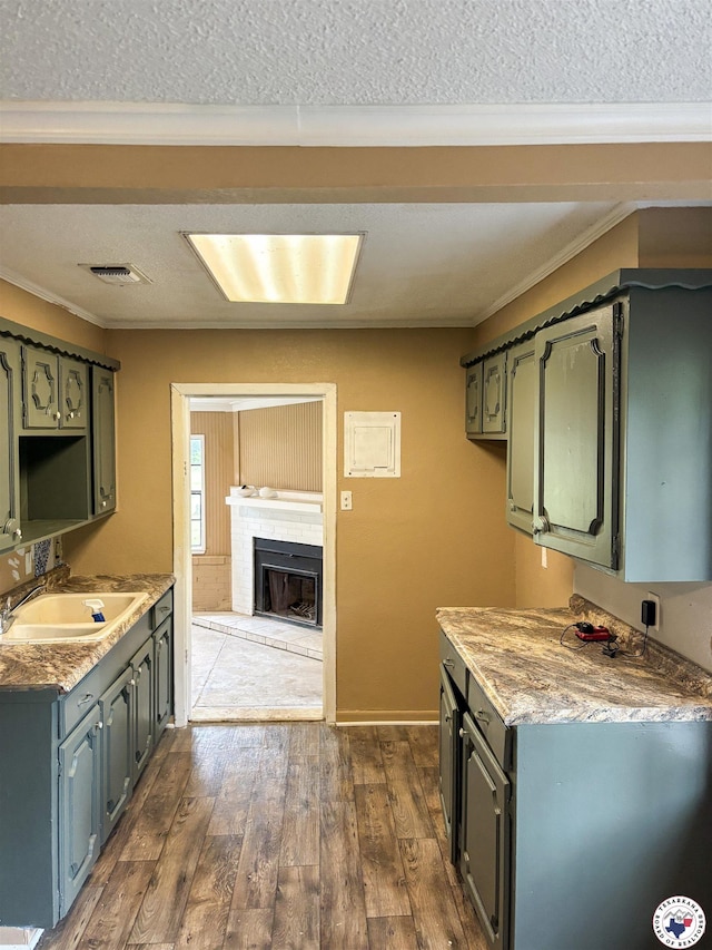 100 Roosevelt St, Hooks, TX 75561 - kitchen featuring dark wood-style flooring, a brick fireplace, ornamental molding, a sink, and a textured ceiling