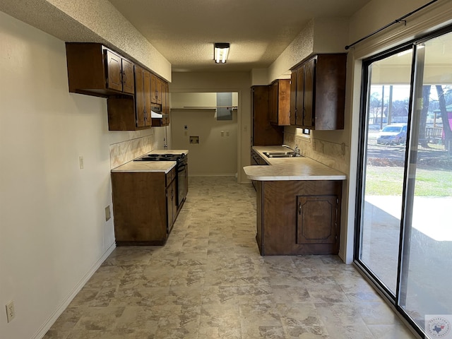 kitchen featuring dark brown cabinetry, sink, black electric range oven, and a textured ceiling