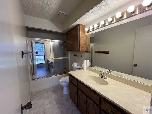 full bathroom featuring vanity, a textured ceiling, shower / bath combination with glass door, and toilet