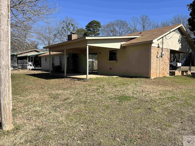 rear view of property with a carport and a yard