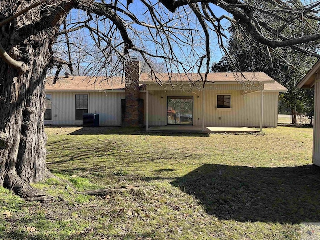 rear view of property with cooling unit, a patio, and a lawn