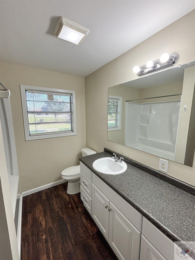 full bathroom featuring wood-type flooring, toilet, vanity, and a textured ceiling