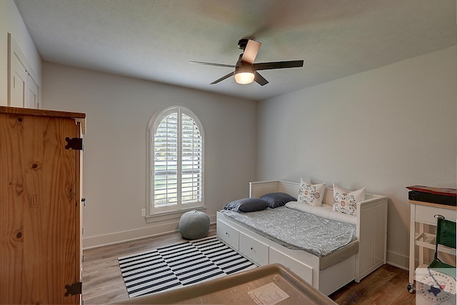 bedroom featuring light wood-type flooring, ceiling fan, and a textured ceiling